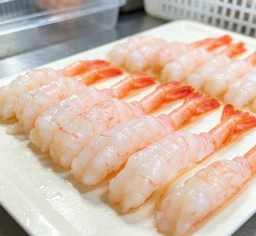 Cooked shrimp skewers with pink tails on a white plate (photo 2 of 3)